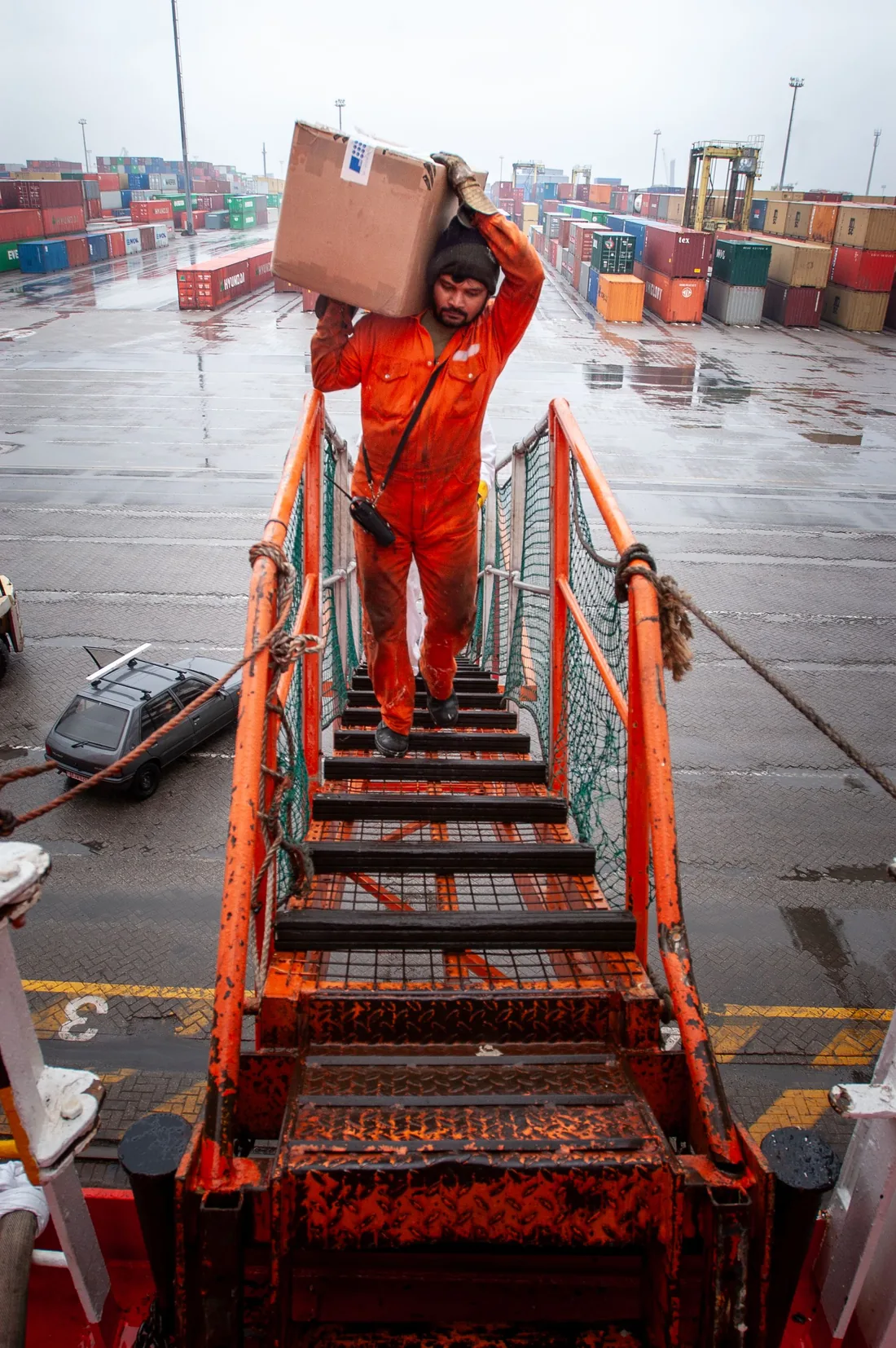 Crew member disembarking down the gangway at a container terminal