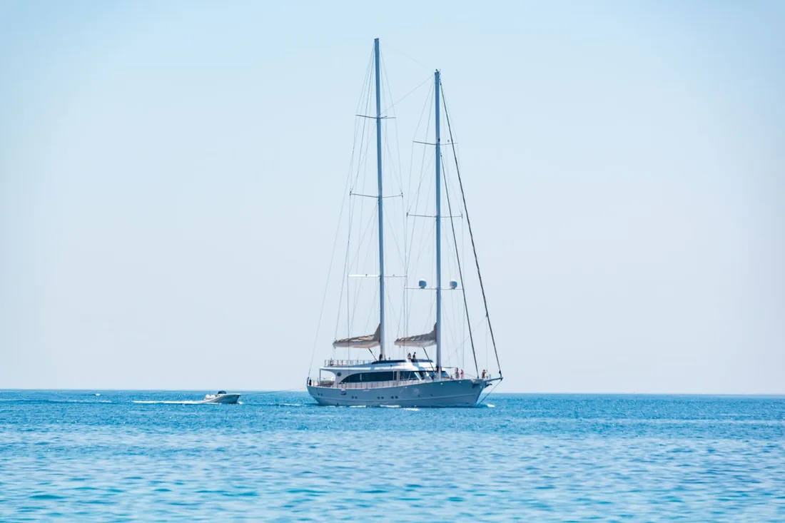 A superyacht under way with its tender alongside